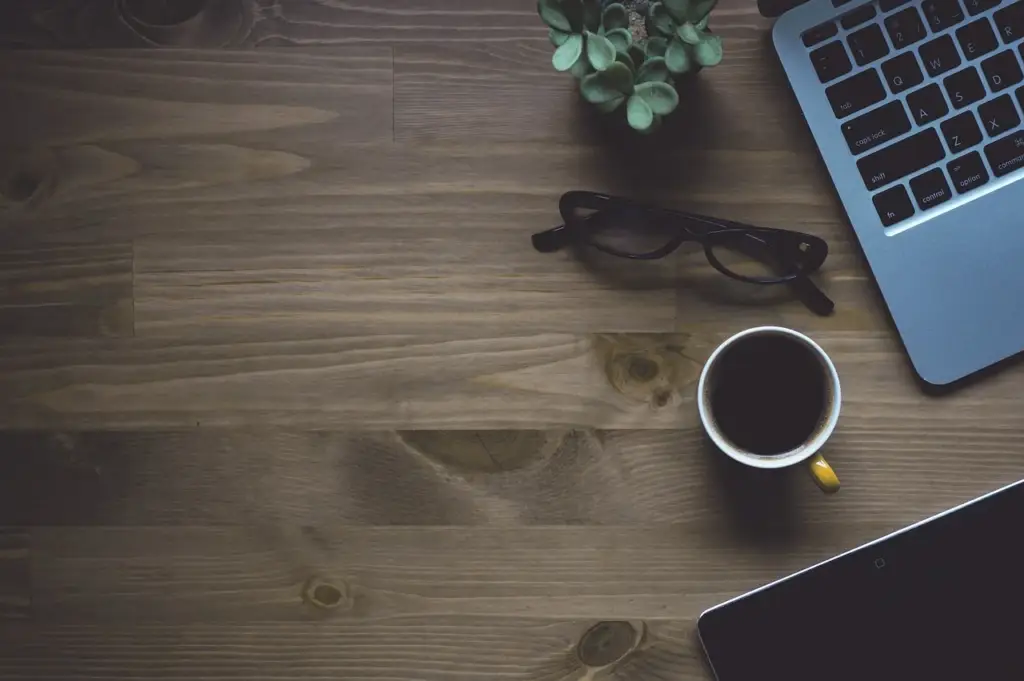 a laptop and coffee cup on a desk with charts visible on screen